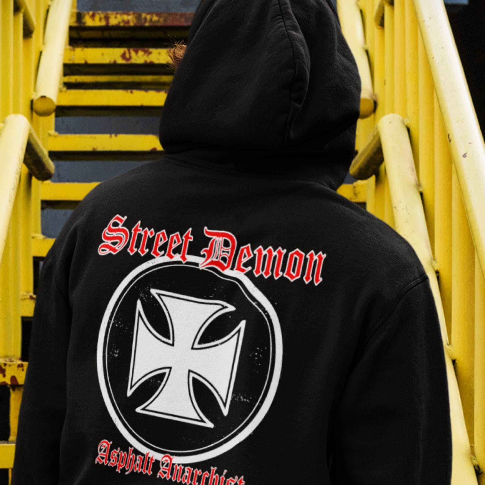 A young hooligan walks up a metal stairway to the elevated train. He is wearing the Street Demon Hoodie from Asphalt Anarchist Clothing Co. KUSTOM KULTURE APPAREL & PRODUCTS - Fuck the Status Quo