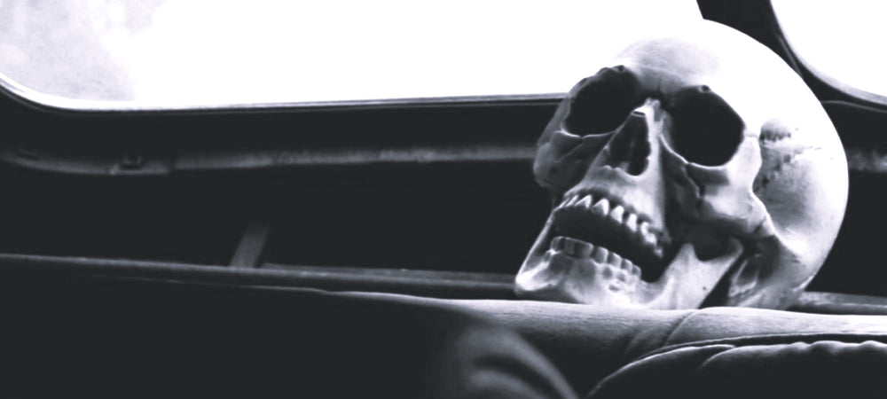 A human skull sits on the back window dash of an old car with the words "Road Rebels & Misfits". Asphalt Anarchist Clothing Co. HOT ROD KUSTOM KULTURE APPAREL & PRODUCTS