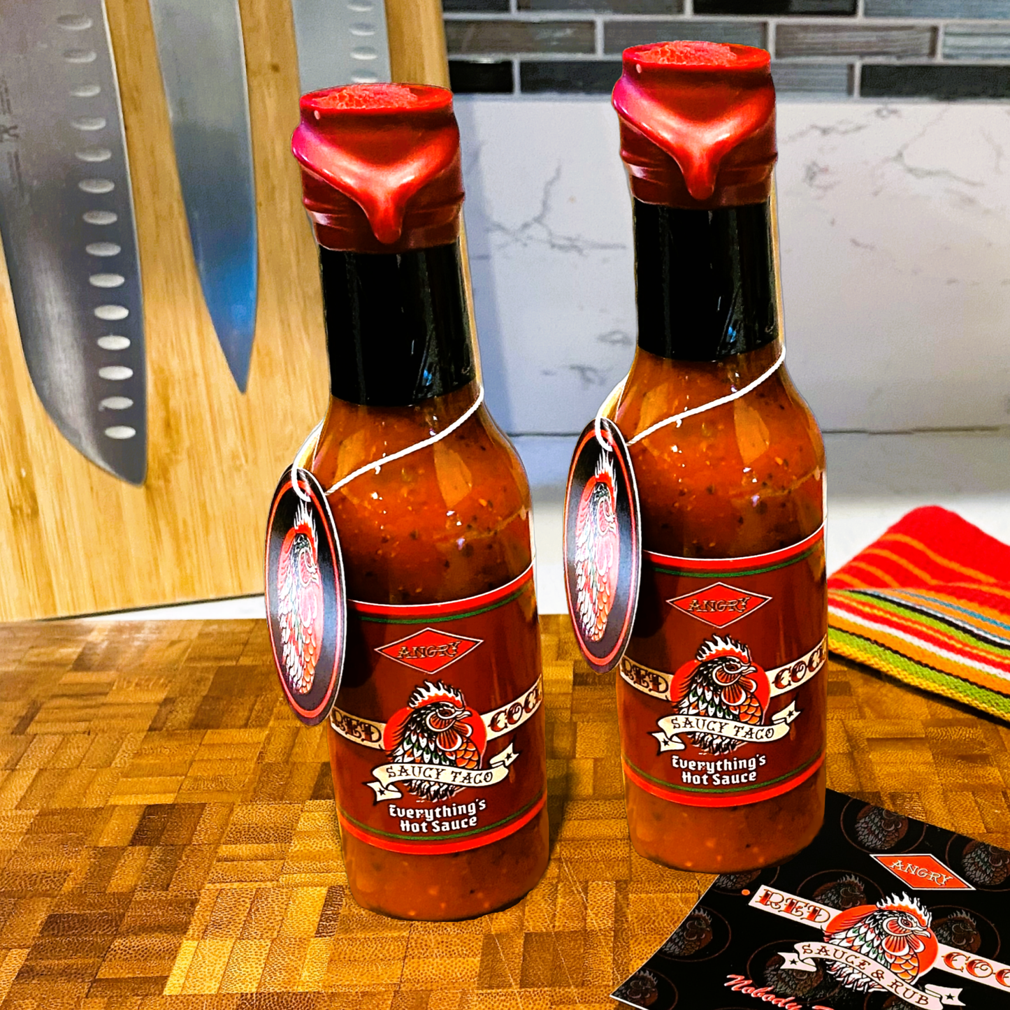 
                  
                    Saucy Taco 2-Pack Everything's Hot Sauce from Angry Red Cock Sauce & Rub sits on a wood chop block. Put our Sauce on your taco! Nobody Beats the Cock. HANDCRAFTED AMERICAN SAUCE & RUB
                  
                