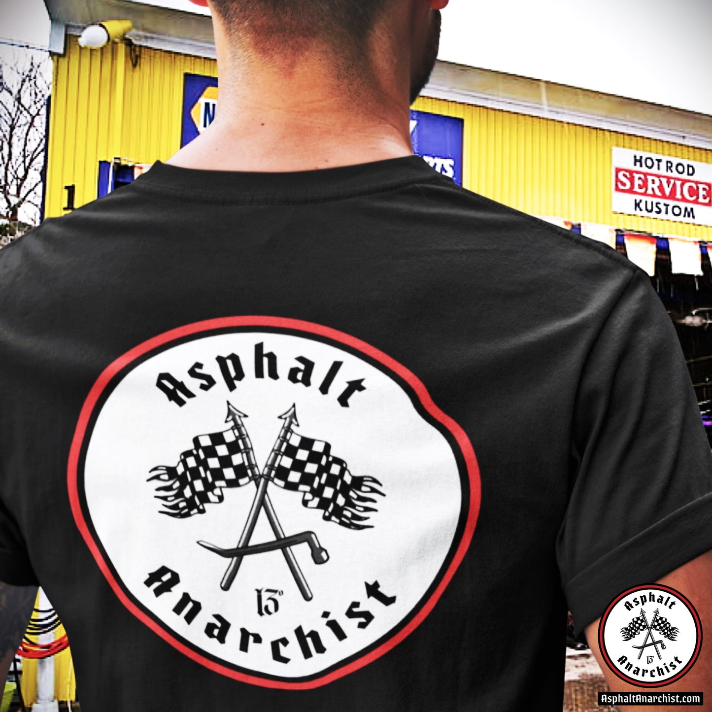A young gearhead is approaching a Hot Rod Kustom garage. He is wearing the Classic Red Line T-Shirt from Asphalt Anarchist Clothing Co. KUSTOM KULTURE APPAREL & PRODUCTS